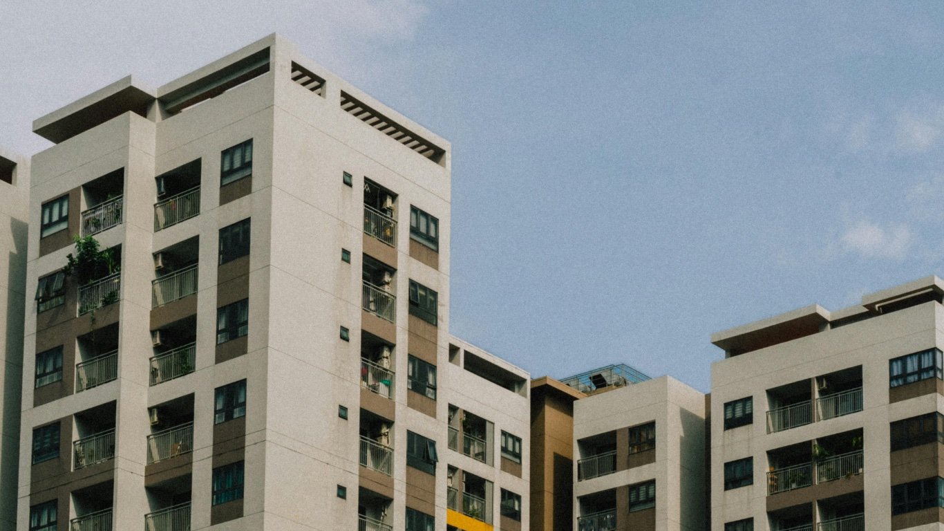 Fachadas de varios bloques de viviendas de balcones acristalados bajo un cielo azul
